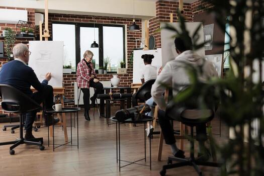 Group of diverse different aged people learning to draw still life objects with proffesional artist, attending group art class, students sitting in classroom drawing with pencil on canvas photo