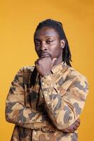 Pensive man brainstorming ideas in studio over yellow background, feeling confused and wondering about idea and question. African american person showing contemplative expression photo