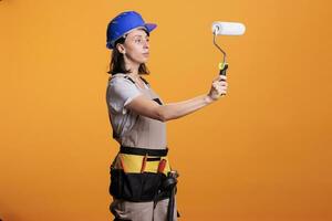 Woman renovator painting walls with roller brush doing interior renovation, working on home improvement. Professional construction worker holding paintbrush and roll to redecorate. photo