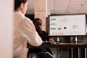 Employee analyzing company financial report dashboard on computer screen, woman working on business research statistics in coworking space, back view. Corporate worker checking analytics photo