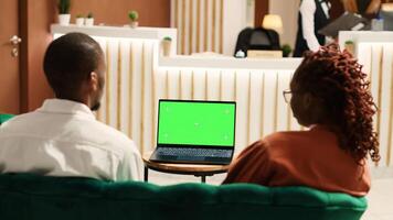 Happy company coworkers away on business trip talking with management on laptop chroma key green screen mock up. Employees travelling for work sitting in hotel lounge waiting to be checked in photo