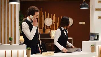 Teamworking professional hotel personnel checking tourists reservation date at check in reception desk. Receptionists coworkers discussing incoming guests booking informations photo