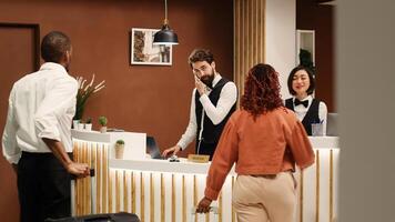 Professional concierge personnel welcoming tourists at reception desk during check in process. Elegant friendly receptionist team greeting vacation trip guests in hotel lobby photo