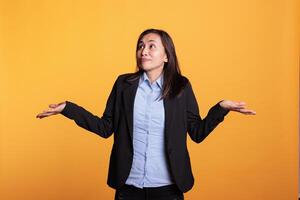 Confused woman shrugging shoulders in studio, doing i dont know sign, having doubtful facial expression. Uninterested filipino model feeling clueless and puzzled about question answer. photo