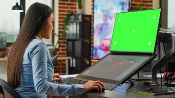 Female office worker using game developing interface and greenscreen display on monitors. Artistic editor working with blank chroma key template on isolated copyspace, planning 3d project. photo