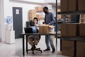 Warehouse employees checking customer helmet order before preparing product for delivery while discussing shipping detalies. Manager and supervisor working in delivery department in warehouse photo