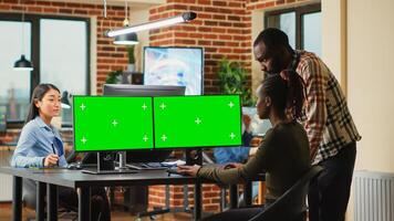 African american workers using greenscreen display on monitors, cheking quality of isolated mockup template. Team of office employees working with blank chroma key copyspace at creatve agency. photo