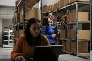 Warehouse asian managers team processing customer order and searching box on shelf. Storehouse package handler and supervisor inspecting goods parcels on rack in storage room photo