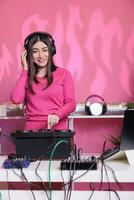 Smiling musician standing at dj table creating musical performance with remix music using professional turntables in studio. Artist performer performing techno song, enjoying nightlife in club photo