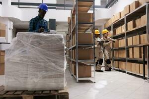 Delivery service storage workers managing parcel receiving and scanning boxes. Caucasian and african american warehouse colleagues using barcode scanner and checking freight documents before shipping photo