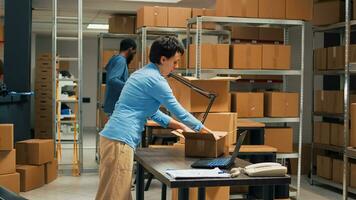 joven puesta en marcha propietario poniendo mercancías en cajas, trabajando con ordenador portátil a hacer bienes inventario antes de Envío productos a clientela. hembra trabajador planificación entrega administración y logística. foto