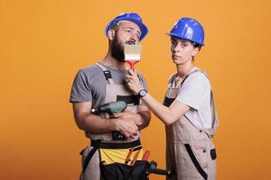 Construction workers yawning and being sleepy in studio, posing with multiple renovating tools. Exhausted repairman and handywoman holding building instruments, being tired and asleep. photo