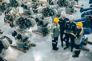 Engineer team diverse working together in modern industrial robotics factory. Engineers people teamwork standing around robot arm in machine assembly plant. photo