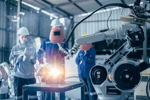 Engineer worker team working control operate small  robot welding arm in metal workshop photo