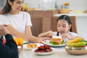 asiático linda hija contento disfrutar comiendo sano comida Mañana comida vegetal ensalada emparedado foto