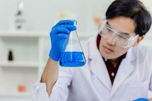 Young Asian scientist man wearing white lab uniform testing research medical formula at laboratory photo