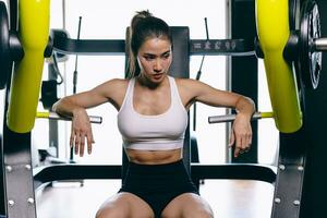 hermosa modelo de asiático mujer deporte sano Delgado formación construir músculo con peso máquina en gimnasio aptitud deporte club foto