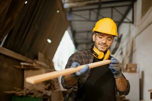 Happy carpenter worker working look at wood panel material for making masterpiece wood crafting furniture. photo