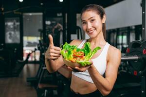 asian young sport woman in fitness sport club with healthy food eating vegetables mix salad diet low calories photo