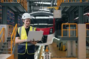 Technician Engineer maintenance service electric train with laptop computer in train repair depot. Train designer in factory. photo