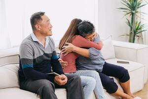 teen girl daughter hug embrace mother sitting with parent at home for consolation care love expression in asian family photo