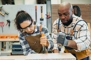 strong woman worker. builder team work. joiner in wood workshop. lady carpenter staff helping man working making furniture. hard work fix wooden board photo