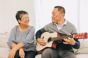 Senior elderly couple lover holiday home activity old man playing guitar music make elder wife happy smile photo