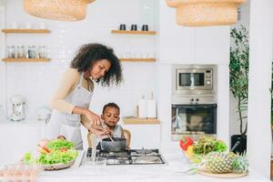 happy african black young mother with her boy lovely cute cooking together at home holiday activity photo