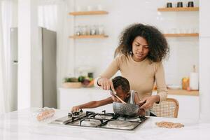 ocupado mamá Cocinando comida en cocina estufa isla a hogar con juguetón traviesamente niño chico estilo de vida Clásico tono foto