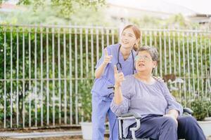 senior elderly adult woman with disability wheelchair in home care nurse doctor or physiotherapist help support relax outdoor photo