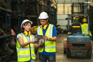 Engineer employee team women worker working together with man work in dirty junkyard old used auto car part warehouse for recycle or repair photo