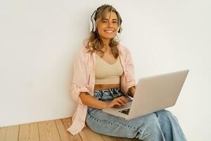 Pretty blond female  student  using lap top , listening online course by lap top and sitting on the floor in living room photo