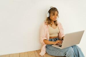 Pretty blond female  student  using lap top , listening online course by lap top and sitting on the floor in living room photo