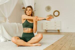 Time for yoga.  Pretty young woman exercising and sitting in yoga lotus position while resting at home. Stylish Scandinavian interior. photo