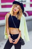 Beautiful sexy blonde girl in casual clothes with perfect  figure  walking around the city. Fashion and city style. Black stylish hat,  short top. Sensual full lips. photo