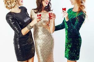 Party and holidays concept. Three glamour women in luxury glitter sequins dress drinking cocktails  and having fun. Hollywood make up, wavy hairstyle. White background. photo