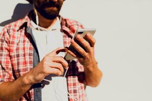 Handsome  hipster male with beard   in sunglasses texting messages via smartphone and blogging in social networks sharing multimedia  near copy space for advertising. photo