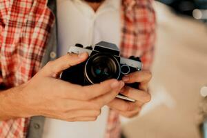 Focus on camera. Details. Man  holding  film camera , making photos. Tourist mane walking in big modern city. photo