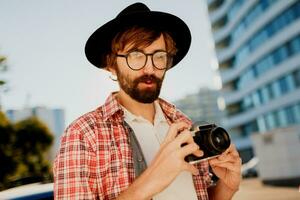 salido hombre con barba con interesante utilizando retro película cámara , haciendo fotos turista melena caminando en grande moderno ciudad.