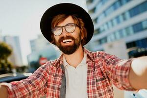 Funny man with beard making self portrait by camera while he traveling in big modern city in Asia. photo