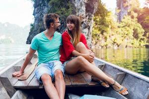 Traveling  couple in love  hugging and relaxing on longtail boat in thai island lagoon. Pretty woman and her handsome  man spending vacation time together . Happy mood. Adventure time. photo