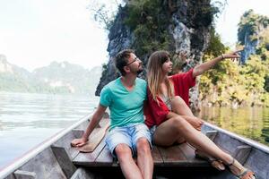 Traveling  couple in love  hugging and relaxing on longtail boat in thai island lagoon. Pretty woman and her handsome  man spending vacation time together . Happy mood. Adventure time. photo