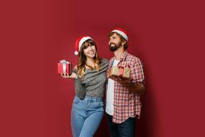 Elegant couple in love posing on red background in fashionable elegant outfit.  New Year mood photo