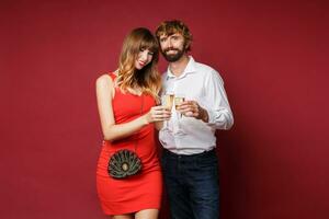 Elegant couple in love posing on red background in fashionable elegant outfit.  New Year mood photo