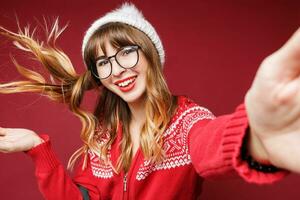 sonriente mujer en invierno atuendo posando en estudio en rojo antecedentes. foto