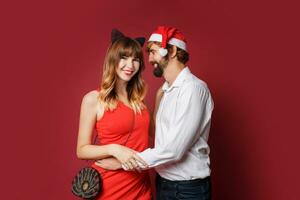 Elegant couple in love posing on red background in fashionable elegant outfit.  New Year mood photo