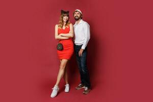 elegante Pareja en amor posando en rojo antecedentes en de moda elegante atuendo. nuevo año estado animico foto