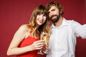 elegante Pareja en amor posando en rojo antecedentes en de moda elegante atuendo. nuevo año estado animico foto