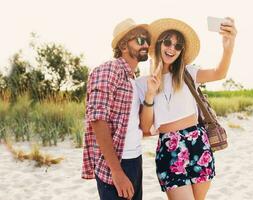 Couple or best friends man and woman having fun on summer sunny beach . Wearing straw hat, sunglasses, stylish  shirts . photo