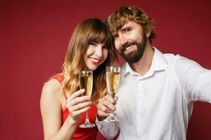 Elegant couple in love posing on red background in fashionable elegant outfit.  New Year mood photo